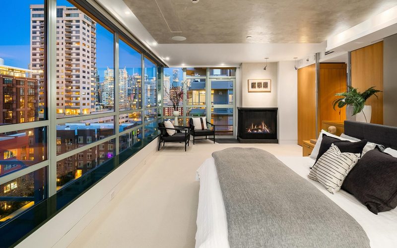 Luxury condo bedroom with floor-to-ceiling city views and fireplace