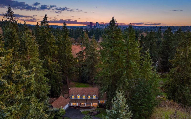 Aerial view of luxury home nestled in evergreen trees in Bridle Trails at twilight
